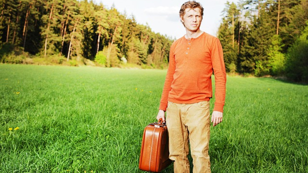 man standing alone holding a suitcase
