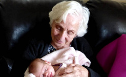 a grandmother (or perhaps a great-grandmother) holding a newborn child